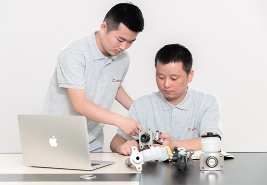 two engineers studying and comparing brake parts for customization